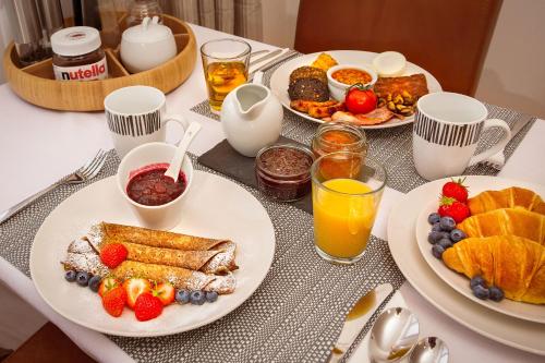 a breakfast table with plates of breakfast foods and drinks at Beechwood Lodge in Alness