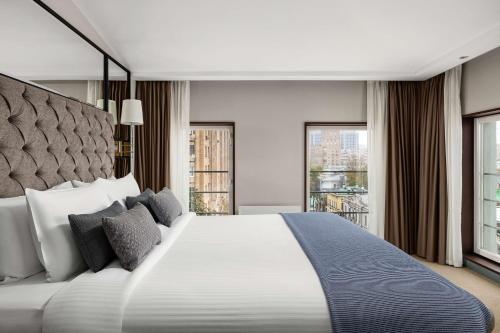 a bedroom with a large white bed with windows at Chekhoff Hotel Moscow Curio Collection By Hilton in Moscow