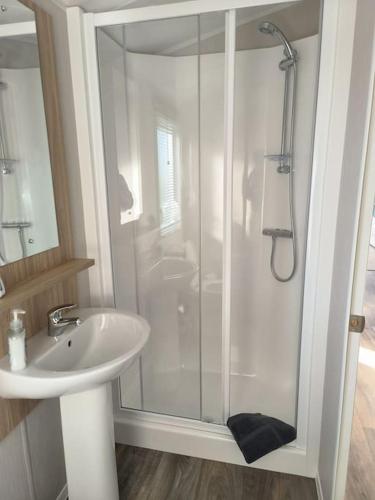 een witte badkamer met een douche en een wastafel bij Oaks 25 in Newton
