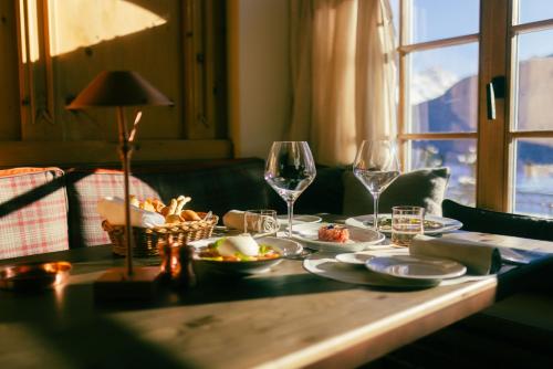 a table with food and wine glasses and a window at Kulm Hotel St. Moritz in St. Moritz