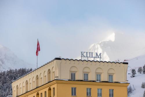 a yellow building with a mountain in the background at Kulm Hotel St. Moritz in St. Moritz