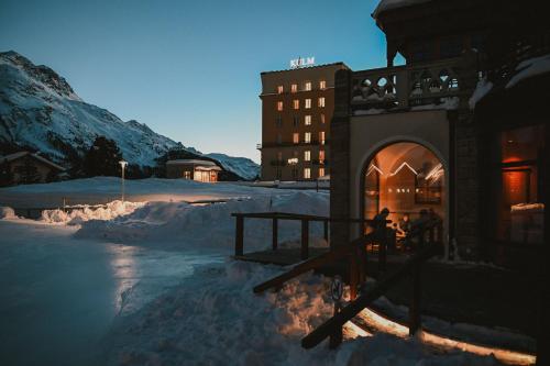 a building in the snow next to a mountain at Kulm Hotel St. Moritz in St. Moritz
