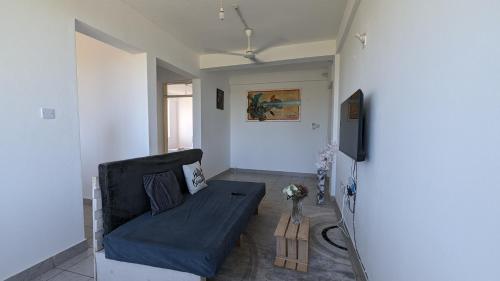 a living room with a couch and a tv at Sea Spray Apartment in Ukunda