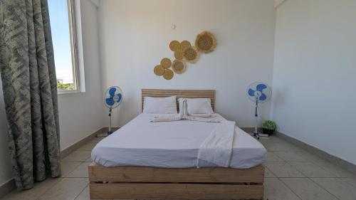 a bedroom with a bed and two fans on the wall at Sea Spray Apartment in Ukunda