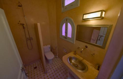 a bathroom with a sink and a toilet and a mirror at Maison d'hôtes Dar Farhana in Ouarzazate