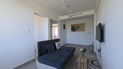 a living room with a couch and a tv at Sea Spray Apartment in Ukunda