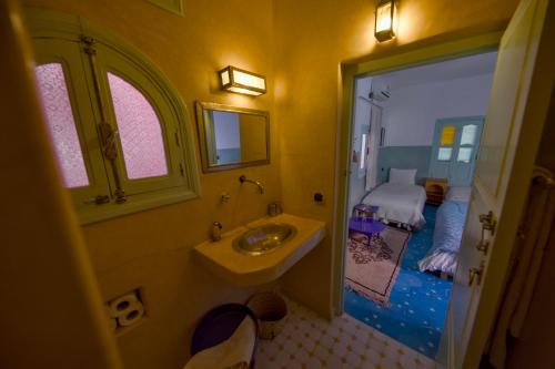 a bathroom with a sink and a bed in a room at Maison d'hôtes Dar Farhana in Ouarzazate