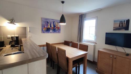 une cuisine avec une table de salle à manger et une télévision dans l'établissement Argousiers 111, à Fort-Mahon-Plage