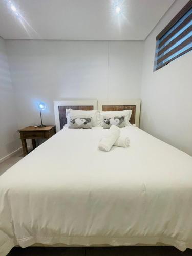 a white bed with white sheets and pillows at Tranquil Retreat in Secure Estate, 2 Bedrooms in Umhlanga