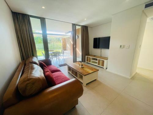 a living room with a brown leather couch and a television at Tranquil Retreat in Secure Estate, 2 Bedrooms in Umhlanga