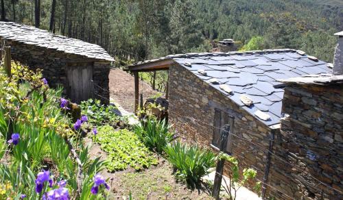 a stone house with a garden and flowers at Retiro do Aguincho in Aguincho