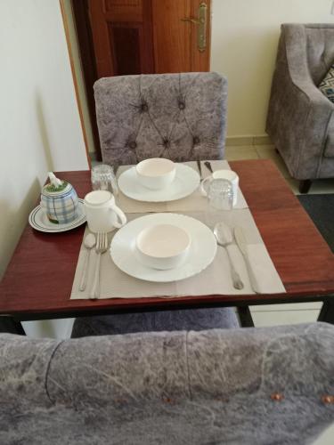 a table with white plates and silverware on it at Home away from home Next to Sky Louge Bamburi in Mombasa