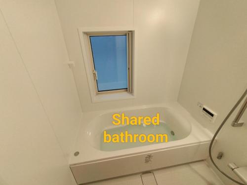 ein Bad mit einer Badewanne und einem Fenster in der Unterkunft Long Stay Takayama in Takayama