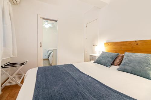 a bedroom with a large white bed with blue pillows at Malaga Center Flat Soho Modern 2BR in Málaga