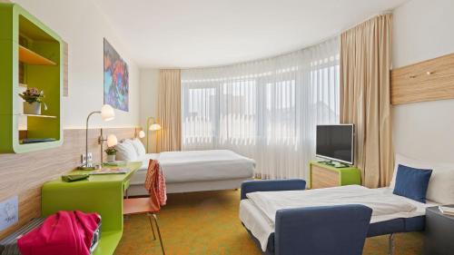 a hotel room with two beds and a desk at Hey Lou Hotel Hildesheim in Hildesheim