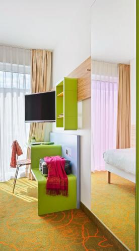 a bedroom with a bed and a desk with a red blanket at Hey Lou Hotel Hildesheim in Hildesheim