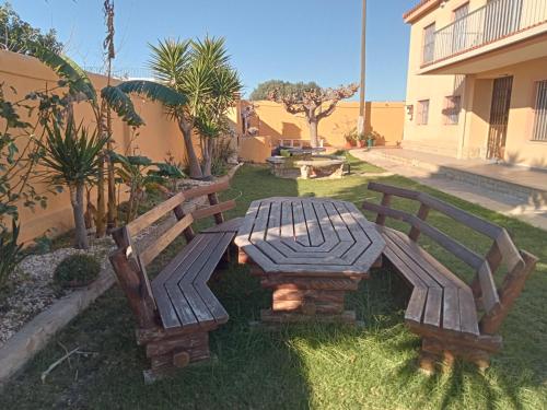 due panchine di legno e un tavolo da picnic in un cortile di JADE a Vinarós