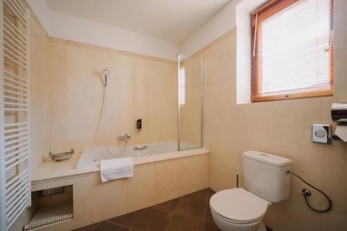 a bathroom with a toilet and a shower and a tub at Boutique Hotel Maraton in Košice