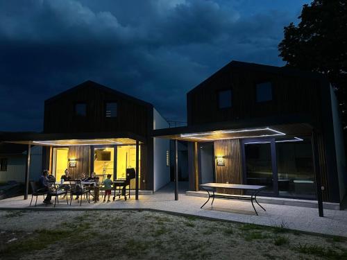 a house with people sitting at tables on a patio at night at ARIA DELUXE Mobile Homes with Terme Čatež Tickets in Čatež ob Savi