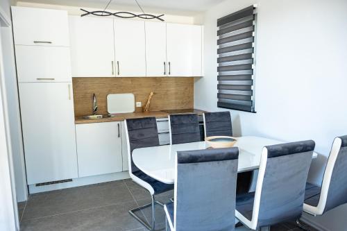a kitchen with white cabinets and a white table and chairs at ARIA DELUXE Mobile Homes with Terme Čatež Tickets in Čatež ob Savi