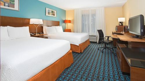 a hotel room with two beds and a desk and a computer at Fairfield Inn & Suites by Marriott Boston Milford in Milford