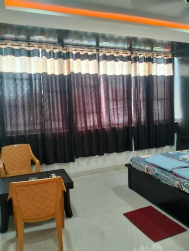 um quarto com cortinas, uma mesa e uma cadeira em Darbar Palace em Gaya