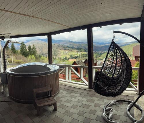 a hot tub on a porch with a hammock and a basket at Порядна Ґаздиня in Yaremche