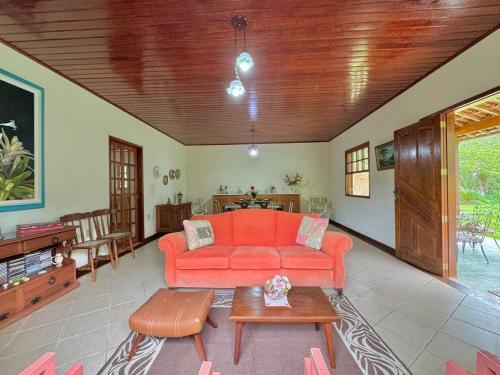 ein Wohnzimmer mit einem orangenen Sofa und einem Tisch in der Unterkunft Casa de campo para relaxar in Nova Friburgo