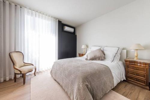 a bedroom with a bed and a chair and a window at Casa Pelourinho de Louredo with pool in Paredes