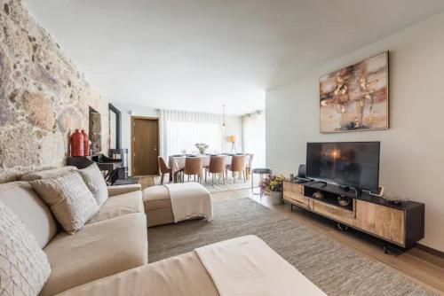 un soggiorno con divano e TV a schermo piatto di Casa Pelourinho de Louredo with pool a Paredes