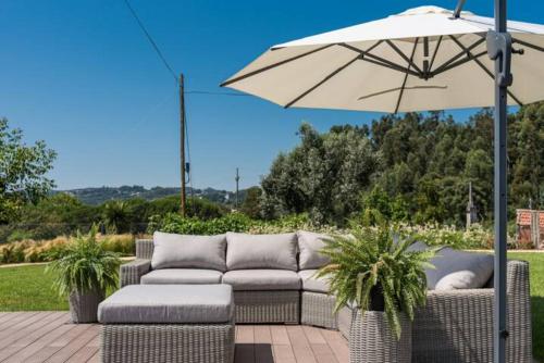 une terrasse avec un canapé et un parasol dans l'établissement Casa Pelourinho de Louredo with pool, à Paredes