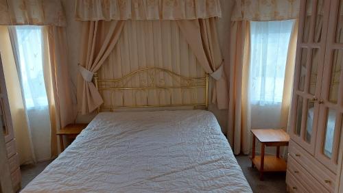 - une chambre avec un lit blanc et 2 fenêtres dans l'établissement 2 bedroom caravan near Llanberis, on the edge of Snowdonia, à Llanddeiniolen