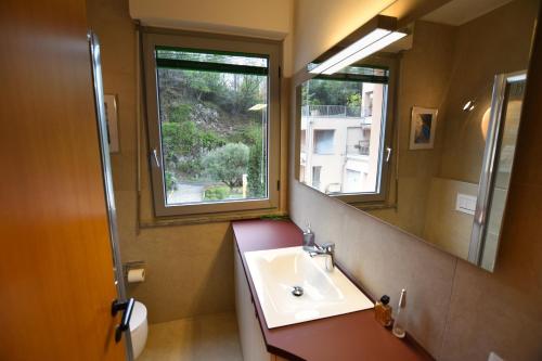 ein Bad mit einem Waschbecken, einem Spiegel und einem Fenster in der Unterkunft 2-Bedroom Lakeview Apartment Bella Gaeta in San Siro