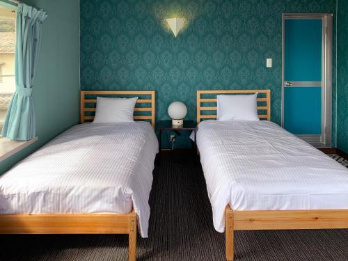 two beds sitting next to each other in a bedroom at HATN HAT Guesthouse ハッツンハットハウス in Shodoshima