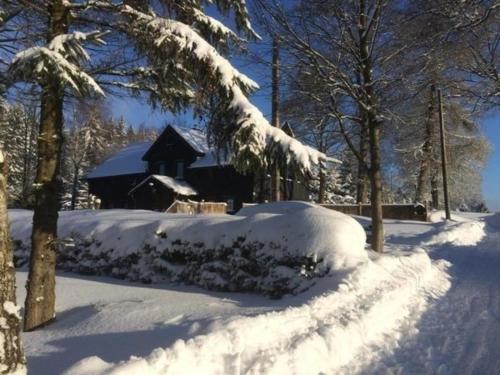 een sneeuwbedekte tuin met een hut op de achtergrond bij Ferienhaus in Klingenthal mit Garten und Terrasse in Klingenthal