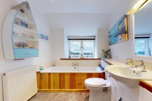 a bathroom with a tub and a sink and a toilet at Captains Cottage Minehead in Minehead