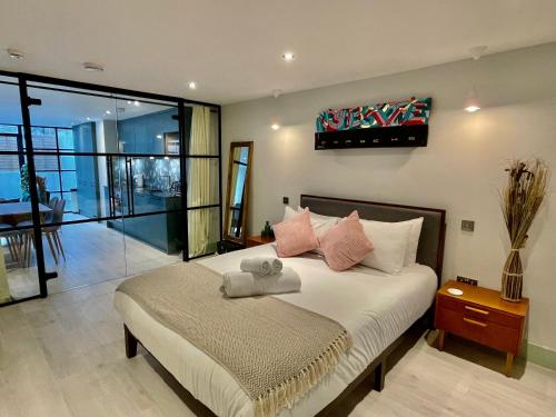 um quarto com uma cama grande e almofadas cor-de-rosa em Hackney 1 Bed Garden Flat em Londres