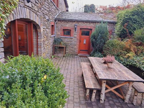 a wooden bench in front of a building with a red door at Dri les Courtils in La Roche-en-Ardenne
