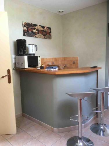 une cuisine avec un comptoir avec des tabourets et un four micro-ondes dans l'établissement Mumbasa - Gîtes du Fozo - Herbignac - La Roche Bernard, à Herbignac