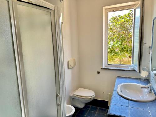 a bathroom with a toilet and a sink and a window at Villa Cice Stintino in Stintino
