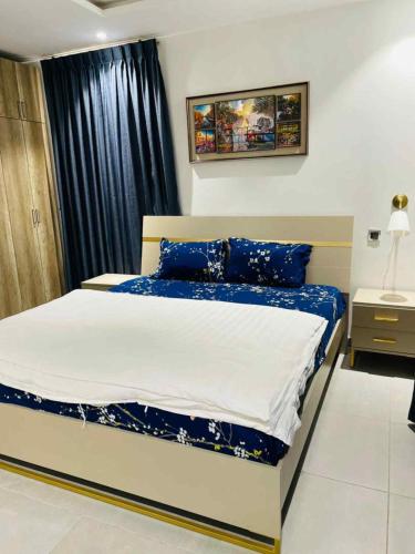 a bedroom with a large bed with blue pillows at Park Apartments in Accra