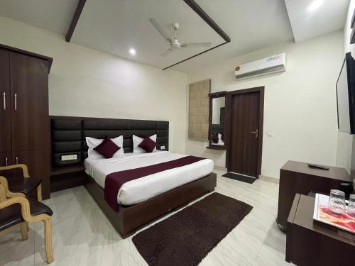 um quarto com uma cama, uma secretária e uma televisão em Hotel AS Royal em Agra