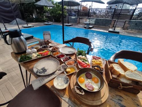 a table with breakfast food next to a swimming pool at ATERNA HOTEL in Dikili