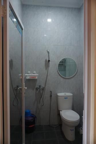 a bathroom with a shower with a toilet and a mirror at Cipada Guesthouse syariah in Sumedang