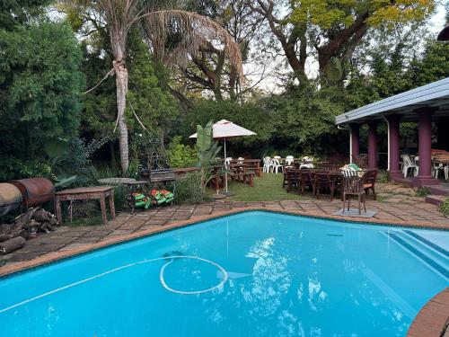 a swimming pool in a yard with a table and chairs at Pebble Fountain Guesthouse in Pretoria