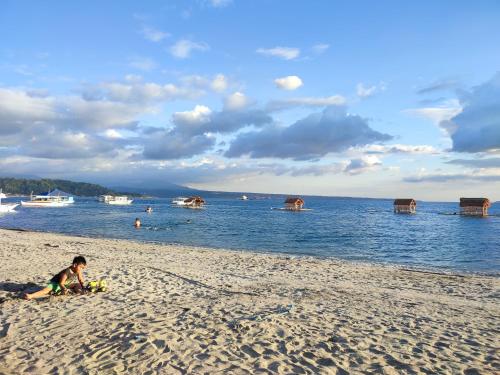 a young child sitting on a sandy beach next to the water at Sunrise Beach Residences u2 in Olongapo