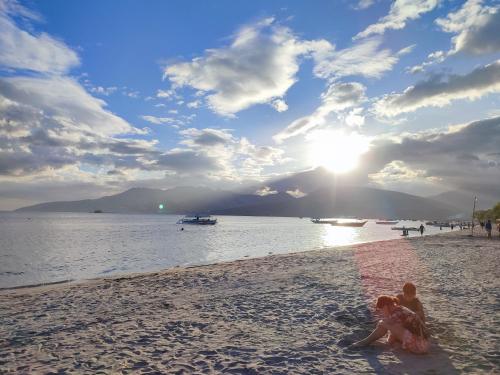 two people sitting on a beach with the sun in the sky at Sunrise Beach Residences u2 in Olongapo