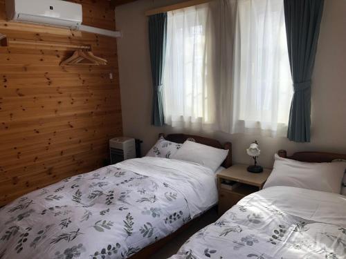 a bedroom with two twin beds and a window at Pension Locomotion in Niseko