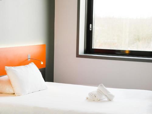 a white bed with a window and two towels at ibis Styles Caen centre gare in Caen