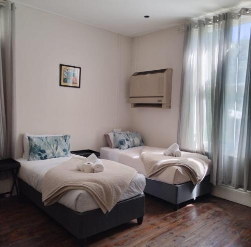 2 camas individuales en una habitación con ventana en HEBA GUEST LODGE en Uitenhage